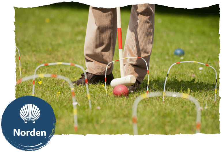 Die Leistung Freizeitservice im Seniorenwohnpark Nordlicht. Ein Mann spielt Croquet im Garten.